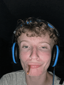 a young man wearing headphones with a worm in his mouth