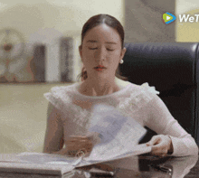 a woman sits at a desk with her eyes closed and a we tv logo in the background