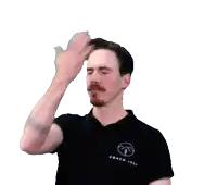 a man wearing a black coach john shirt holds his hand to his forehead
