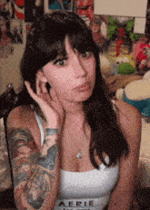 a woman with a tattoo on her arm wears a white aerie tank top