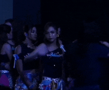 a group of women are standing in a dark room and one of them is wearing a shirt that says ' a '