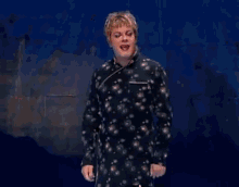 a man in a pajama shirt is standing in front of a blue background