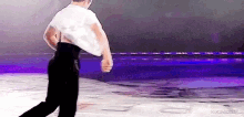 a man in a white shirt and black pants is standing on a stage with his arms outstretched .