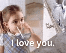 a little girl is drinking water from a pitcher while saying i love you .
