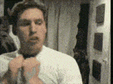 a man wearing a white shirt and tie is adjusting his tie