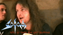 a man with long hair stands in front of a sign that says " hated by those who can t begrudge "