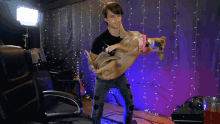 a man is holding a dog in his arms and the dog is wearing a pink bandana