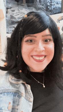 a woman wearing a black shirt and a denim jacket smiles