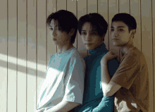 three young men are standing next to each other in front of a striped wall
