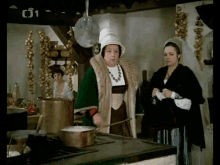two women standing in a kitchen with the number 01 on the bottom left