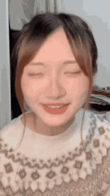 the girl is wearing a sweater and has her eyes closed .