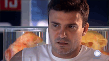 a man in a white shirt is standing in front of a glass container of pizza