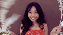a woman in a red dress is smiling and holding a flower in front of a wall that says i want oscar