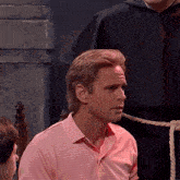 a man in a pink and white striped shirt is sitting in a chair