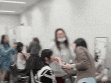 a blurry picture of a group of people including a woman wearing a mask