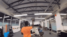 a man in an orange shirt stands in an office