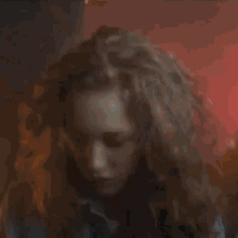 a close up of a woman 's face in a dark room with a red light behind her .