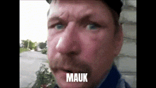 a close up of a man 's face with the word mauk on the bottom right
