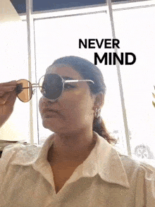 a woman wearing sunglasses with the words `` never mind '' written above her