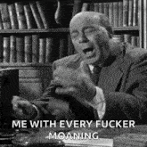 a man in a suit and tie is sitting at a desk making a funny face and screaming .
