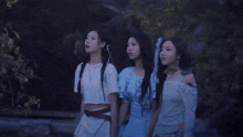 a group of people standing in a field with a large moon in the sky