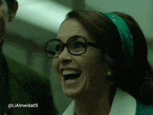 a woman wearing glasses and a green headband is laughing with the hashtag lialmeida05