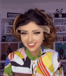 a woman wearing a colorful shirt and a lace front wig is smiling .