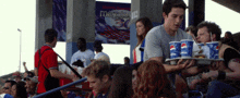 a man is carrying a tray of pepsi cups in front of a crowd