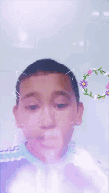 a young boy with a flower crown on his head smiles for the camera