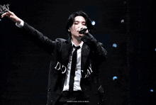 a man in a suit and tie is singing into a microphone with the word decay written on his shirt