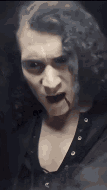 a man with long curly hair is wearing a black shirt with skulls on it