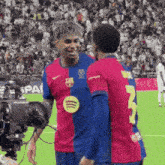 two soccer players are talking on the field and one has the number 3 on his jersey
