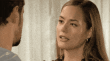 a man and a woman are looking at each other and the woman is crying