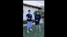 two young men are standing next to each other in front of a building .