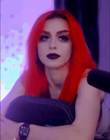 a woman with red hair is sitting in front of a microphone and wearing a watch .