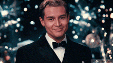 a man in a tuxedo and bow tie is smiling in front of a blurry background with gif-finder.com at the bottom