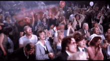 a crowd of people are sitting in a stadium watching a game and holding balloons .
