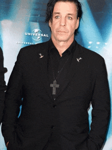 a man in a black suit stands in front of a universal advertisement