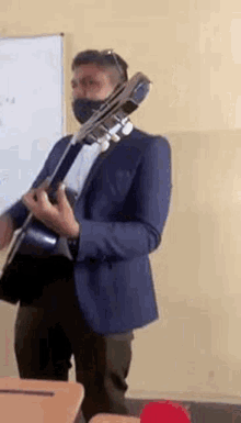 a man in a suit is playing a guitar in a classroom .
