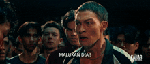 a group of young men are standing in a line and one of them says " malukan dia "