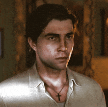 a man wearing a cross necklace looks at the camera
