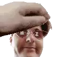 a man wearing glasses and a hat is being hit by a hand .