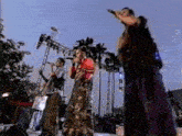 a group of people are standing on stilts on a stage singing into microphones .