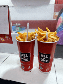 two red all in one cups filled with french fries on a counter