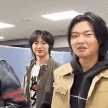 a group of young men are standing next to each other in a room and one of them is making a funny face .