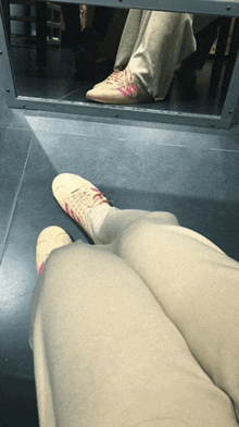 a person 's feet are visible in a mirror and they are wearing pink adidas shoes
