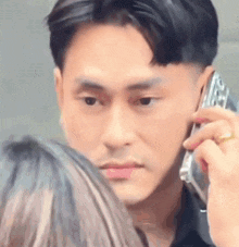 a man is talking on a cell phone while a woman watches .