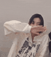 a person wearing a white hoodie is covering their face with their hands .