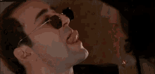a man and a woman are kissing in a room . the woman is wearing sunglasses .