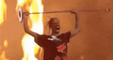 a man is holding a sword in front of a wall of fire .